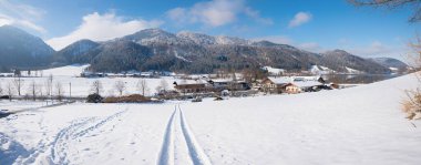 winter hiking path with view to Fischhausen, bavarian alps. bright sunshine and snow covered landscape clipart