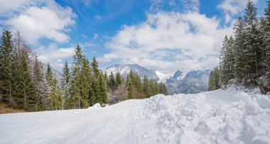 heaps of snow beside the groomed ski run Spitzingsee, view to Taubenstein ski resort at the opposite side. landscape and winter sport area upper bavaria. clipart