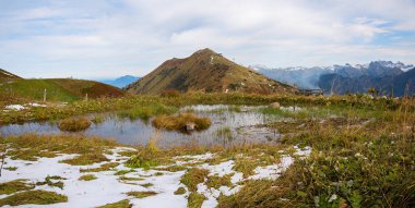 small pond with snow around, view to Fellhorn mountain, allgau alps. hiking destination near Oberstdorf, south germany clipart