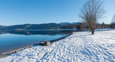 Karlı göl kıyısı Walchensee 'nin karşı tarafında çıplak ağaç ve dağlar var. Panorama manzarası kışın Yukarı Bavyera. 