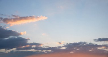 Aydınlatılmış bulutlu mavi gökyüzü arkaplanı ve gün batımından gelen pembe ışık, sağ tarafta boşluğu kopyala