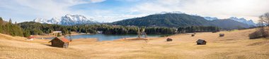 wide panorama landscape lake Geroldsee, meadow with huts, view to Wetterstein and Karwendel mountains, upper bavaria in march clipart