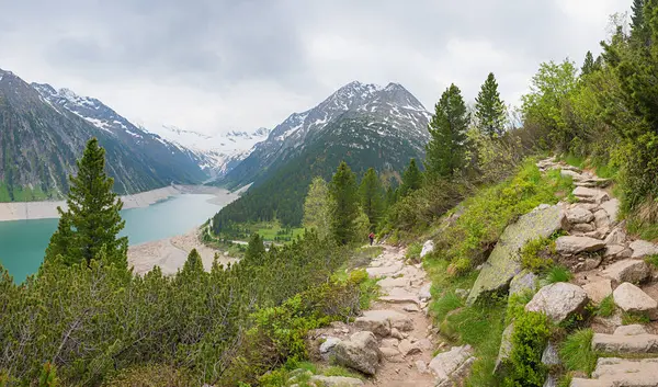 Schlegeis Baraj Gölü 'nden yukarı doğru kayalık dağlık patika. Yeşil dağ çamları ve gri bulutlar. manzara Zillertal Alpler Avusturalya.