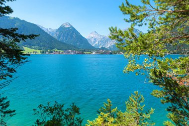 Achensee Gölü 'nün üzerinden Karwendel dağlarındaki Pertisau tatil beldesine. Sol ve sağ tarafta yeşil köknar dalları var. manzara tyrol, austria
