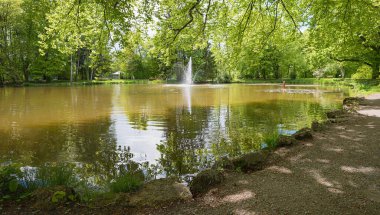 Irlachsee Gölü kaplıca bahçesi Bad Aibling 'de, etrafında fıskiye ve yeşil ağaçlar var. Yukarı Bavyera manzarası