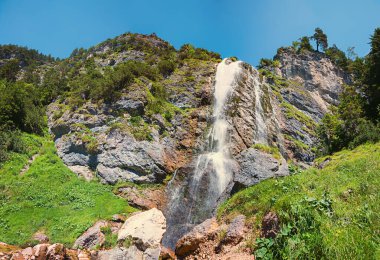 Tyrolean Alplerinde dik bir kaya yüzeyindeki Dalfazer şelalesinde etkileyici bir şelale, yukarıdaki mavi gökyüzü. Achensee Gölü yakınlarındaki manzara ve yürüyüş rotası.