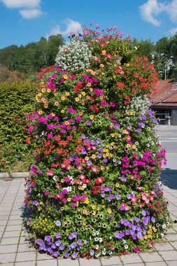 decorative flower column, planted with multicolored petunias and geraniums, located at Ludwig-Erhard-Platz, tourist resort Gmund. clipart