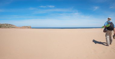 Elinde ekipman olan bir adam, Ufukta Atlantik Okyanusu 'nda, Sandy Bordeira sahilinde yürüyor. Costa Vicentina Portekiz 'de tatil. boşluğu ortaya kopyala. 