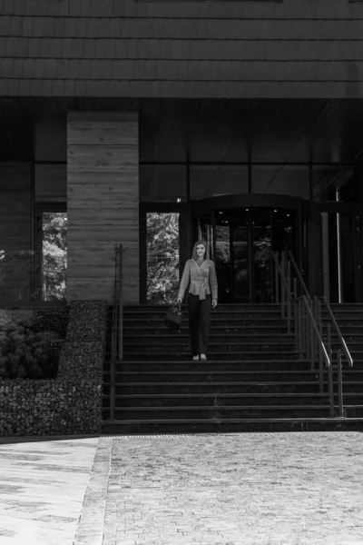 Bir iş binasının yanında şık giyinmiş güzel bir bayanın siyah beyaz fotoğrafı.