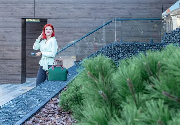 Kızıl saçlı güzel bir kız şehir caddesinde bir şey arıyor.