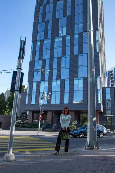 Kızıl saçlı güzel bir kız şehir sokaklarında yürüyor.