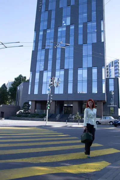 Kızıl saçlı güzel bir kız şehir sokaklarında yürüyor.