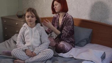 Anne kızının saçını tarıyor. Kadın sabahları güzel kızlarının saçlarını tarıyor. Anne, kızının kuyruğunun saç stilini, yavaş hareketlerini yapıyor. Çocuk bakımı ve annelik kavramı.