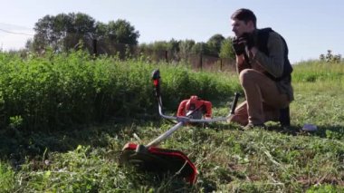 Genç bir adam tarladaki yaşlı böğürtlen biçme makinesini ayarlıyor.