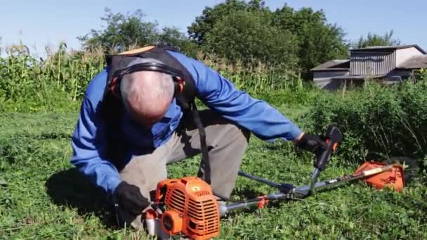 Staruszek Przygotowuje Przycinarkę Benzyny Koszenia Trawy Proces Zbioru Siana Rolnictwie — Wideo stockowe