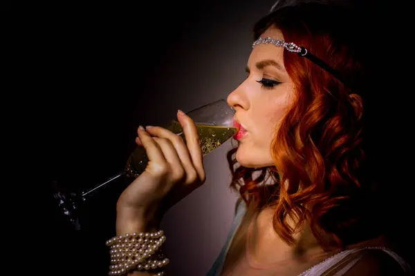 Bir kadeh şampanyası, saçı ve makyajı olan güzel bir kızın fotoğrafı.