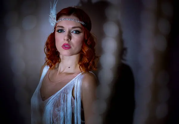 Kızıl saçlı, 1920 'lerin modasını andıran şık beyaz elbiseli genç bir kadın. Tüylü parlak bir saç bandıyla görünüşü tamamlanmış. Zarafet ve klasik bir cazibe katıyor.. 