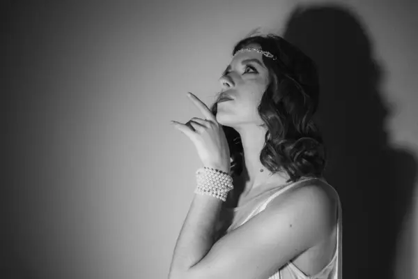 Saçları ve makyajı eski moda olan güzel bir kızın siyah beyaz fotoğrafı.