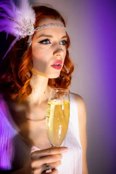 Bir kadeh şampanyası, saçı ve makyajı olan güzel bir kızın fotoğrafı.