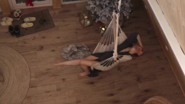 Tahta bir evin ortasında, hamakta sallanan güzel bir kadın. Sıcak, rahatlatıcı bir atmosfer. 