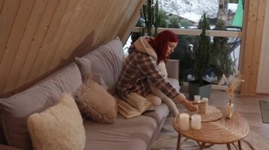 Ev kıyafetleri içinde kızıl saçlı gülümseyen bir kız: kulaklarla süslenmiş kapüşonlu lüks pijamalar. Atmosfer sıcak, rahat ve rahat.. 