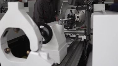 Modern torna tezgahında bir metal parçasını eğitim veya üretim mühendisliği atölyesi koşullarında makineleme işlemi. Operatörün işi, ekipman ayarları ve güvenlik temelleri gösterilir.
