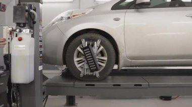 Tekerlek geometrisini kontrol etmek için tribün kullanan bir elektrikli aracın tekerlek hizalanmasının teşhisi. Tekerleklere bir ölçüm cihazı bağlanmış.,