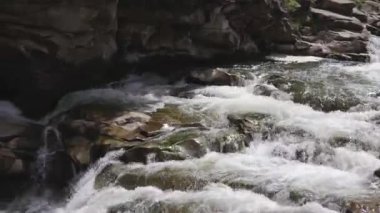 Güçlü dağ nehri ıslak kayaların üzerinden köpüklü beyaz akıntılarla akıyor. Güneş ışığındaki doğal vahşi su akıntısı doğa, seyahat ve meditasyon için mükemmeldir..