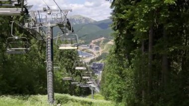 Dağ oteli ve Carpathian tepeleri panoramik manzaralı yeşil yaz ormanı üzerinde hareket eden bir teleferik. Manzara doğa, eko seyahat, turizm altyapısı, Bukovel, Ukrayna.