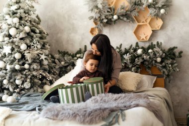 Bebekli bir anne Noel 'de hediye kutularıyla eğleniyor. Bebek sürpriz yapmak ve evde oynamak için heyecanlı. Aile kutlaması ve yeni yıla hazırlık.