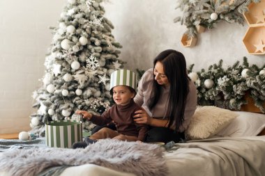 Bebekli bir anne Noel 'de hediye kutularıyla eğleniyor. Bebek sürpriz yapmak ve evde oynamak için heyecanlı. Aile kutlaması ve yeni yıla hazırlık.