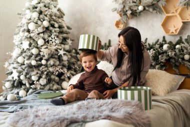 Bebekli bir anne Noel 'de hediye kutularıyla eğleniyor. Bebek sürpriz yapmak ve evde oynamak için heyecanlı. Aile kutlaması ve yeni yıla hazırlık.