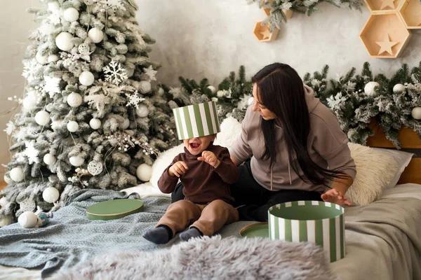 Bebekli bir anne Noel 'de hediye kutularıyla eğleniyor. Bebek sürpriz yapmak ve evde oynamak için heyecanlı. Aile kutlaması ve yeni yıla hazırlık.