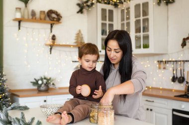 Anne ve oğlu Noel süslemeli mutfakta oynuyor ve eğleniyorlar. Mutlu aile tatili bekliyor.