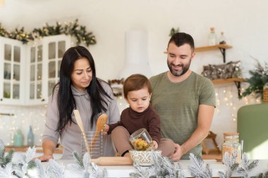 Anne, baba ve oğul Noel süslemeli mutfakta oynayıp eğleniyorlar. Mutlu aile tatili bekliyor.