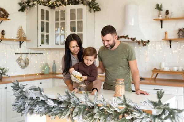 Anne, baba ve oğul Noel süslemeli mutfakta oynayıp eğleniyorlar. Mutlu aile tatili bekliyor.