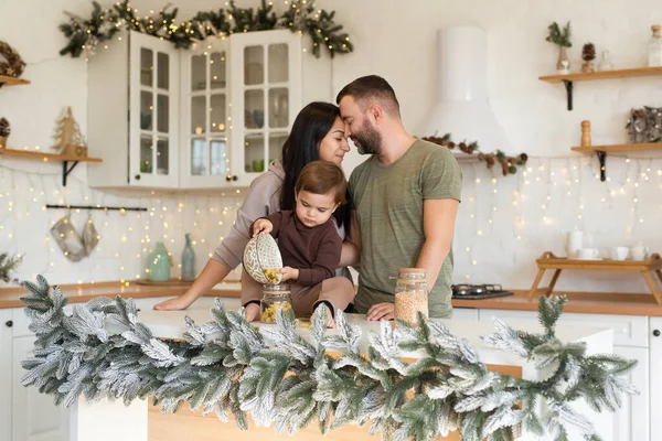 Anne, baba ve oğul Noel süslemeli mutfakta oynayıp eğleniyorlar. Mutlu aile tatili bekliyor.