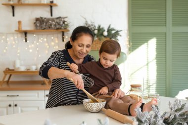 Büyükanne ve çocuk Noel süslemeli mutfakta oynayıp eğleniyorlar. Mutlu aile tatili bekliyor.