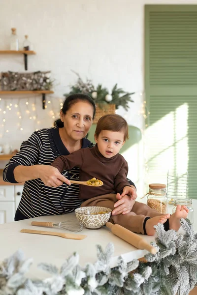 Granny and boy playing and having fun at Christmas decorated kitchen. Happy family waiting for the holidays