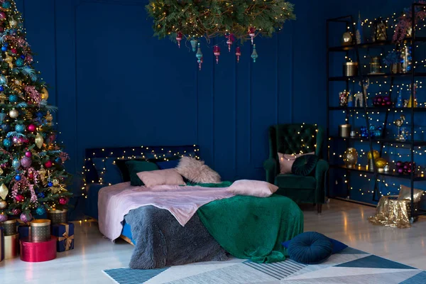 Christmas decor. Bedroom in dark colors with large bed. The interior is decorated with garlands and Christmas tree. Modern style. Cozy Christmas home interior