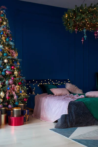 Christmas decor. Bedroom in dark colors with large bed. The interior is decorated with garlands and Christmas tree. Modern style. Cozy Christmas home interior