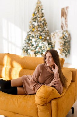 Mutlu genç ve güzel bir kadın Noel 'i kutluyor. Kazaklı kız Noel ağacının arka planında poz veriyor.