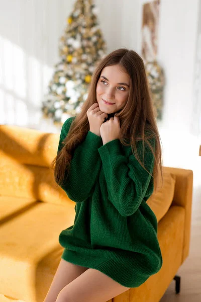 クリスマスを祝う幸せな若い美しい女性 女の子で緑のセーターポーズの背景にクリスマスツリー — ストック写真