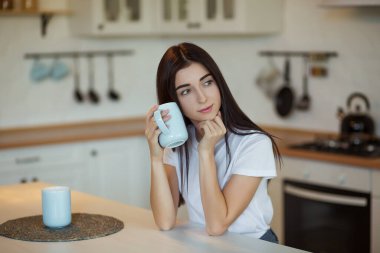 Güzel genç bayan evde bir fincan kahve içiyor.