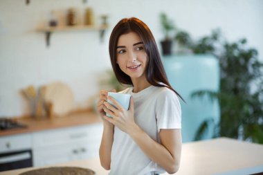 Güzel genç bayan evde bir fincan kahve içiyor.