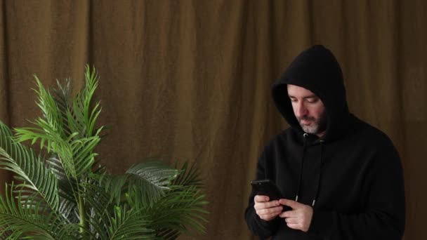 Mannen Luvtröja Använder Smartphone Nära Den Gröna Växten — Stockvideo