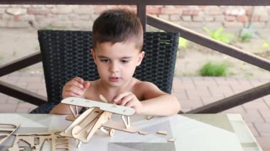 Çocuk oyuncak bir tahta uçak yapıyor. Atölyedeki çocuk el işi yapıyor..
