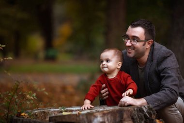 Sevimli küçük oğlan ve babası. Baba ve oğul, sonbahar günü şehir parkında eğleniyorlar..