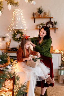 Mutlu Noeller ve mutlu tatiller. Neşeli anne ve tatlı kızı hediyelerini değiştiriyorlar. Ebeveyn ve küçük çocuk içeride Noel ağacı yakınında eğleniyorlar. Odasında hediyeler olan sevgi dolu bir aile