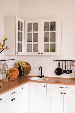 Wooden counter with white sink and utensils near light wall in kitchen.